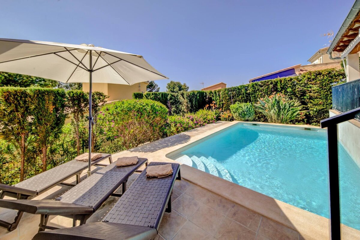 A swimming pool with a white umbrella and lounge chairs