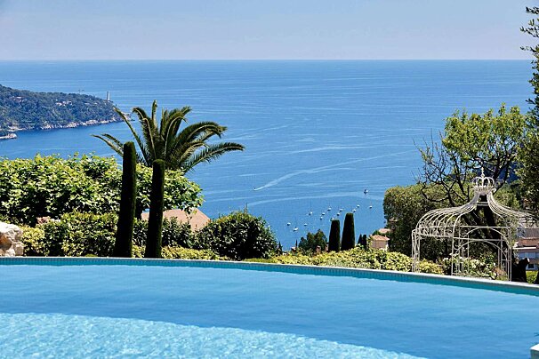 A swimming pool overlooking the ocean with a gazebo in the foreground