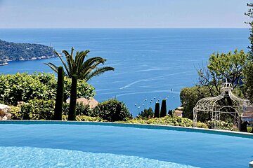 A swimming pool overlooking the ocean with a gazebo in the foreground