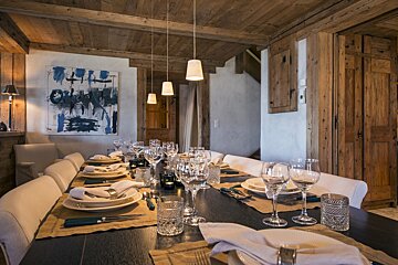 A dining room with a painting on the wall above the table