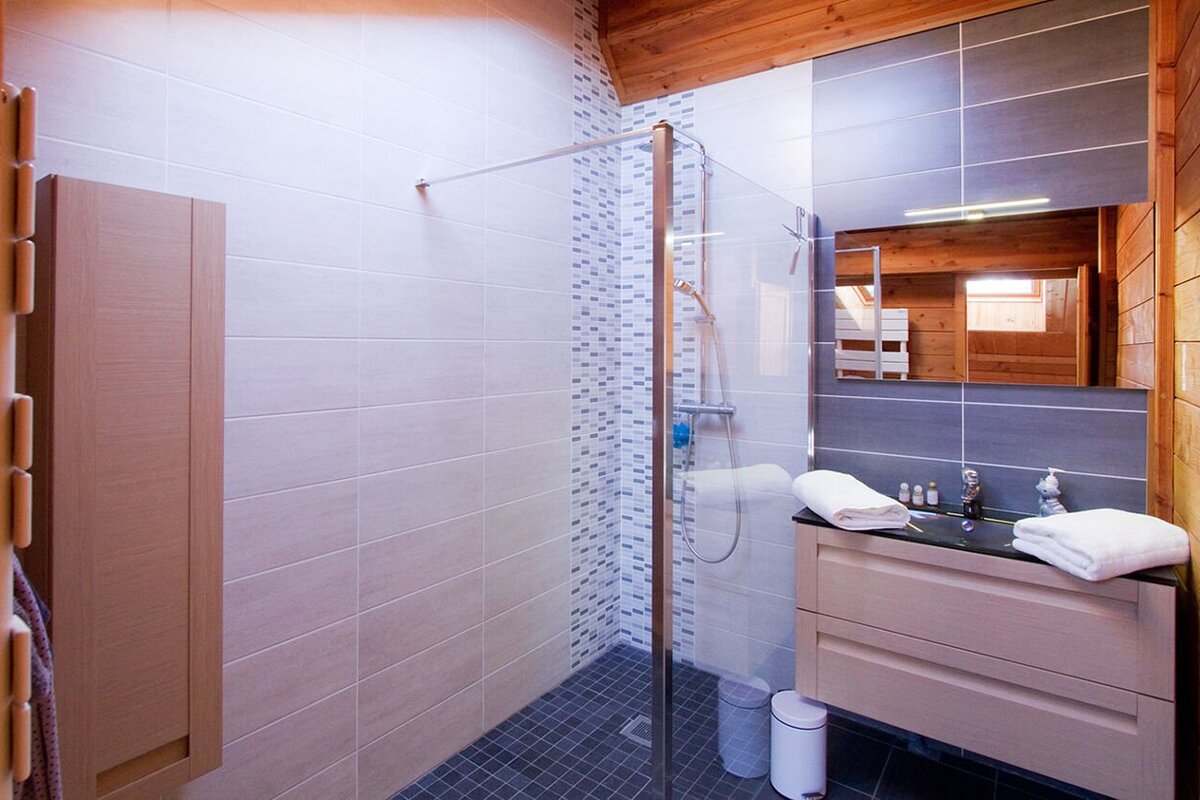 A bathroom with a walk in shower and a sink
