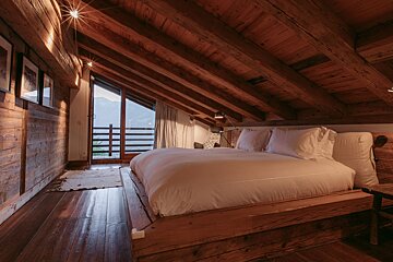 A bedroom with a wooden ceiling and a bed