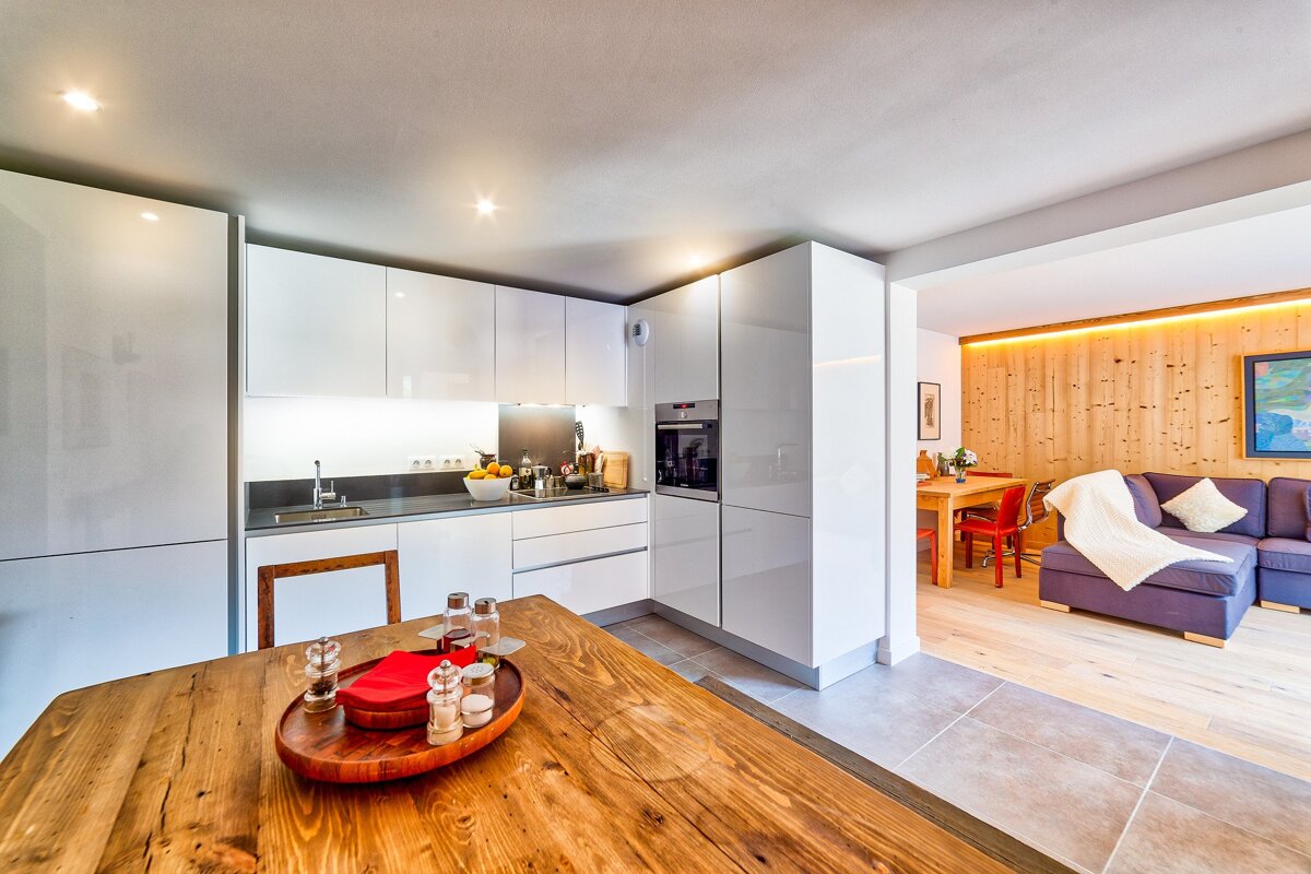 A kitchen with white cabinets and a wooden table