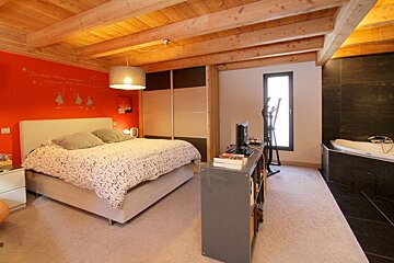 A bedroom with a large bed and a bathtub