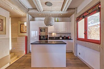 A kitchen with white cabinets and a red window