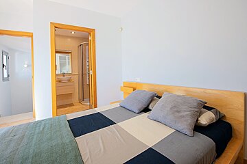 A bedroom with a bed and a bathroom in the background