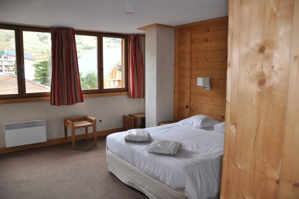 A hotel room with a bed and two windows