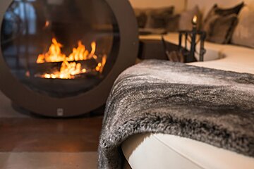 A living room with a fireplace and a fur blanket
