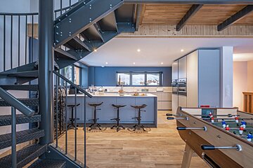 A kitchen with a foosball table and a spiral staircase