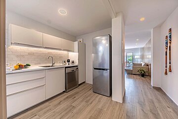 A kitchen with white cabinets and a stainless steel refrigerator