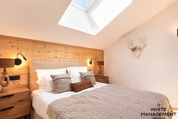 A bedroom with a bed and a deer head on the wall