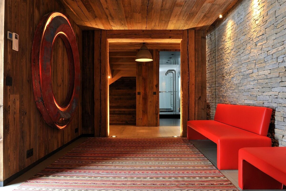 A hallway with wooden walls and a red bench