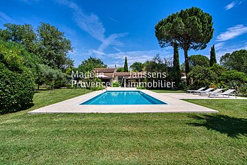 A large swimming pool is surrounded by lawn chairs and a sign that says made in janssens provence immobilier