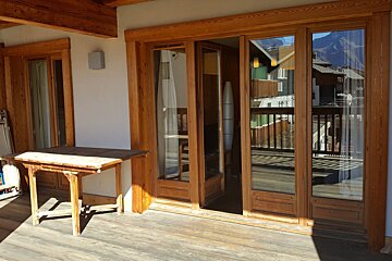 A wooden table sits in front of a sliding glass door