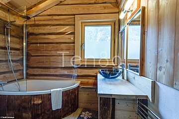 A bathroom in a log cabin with a tub and sink