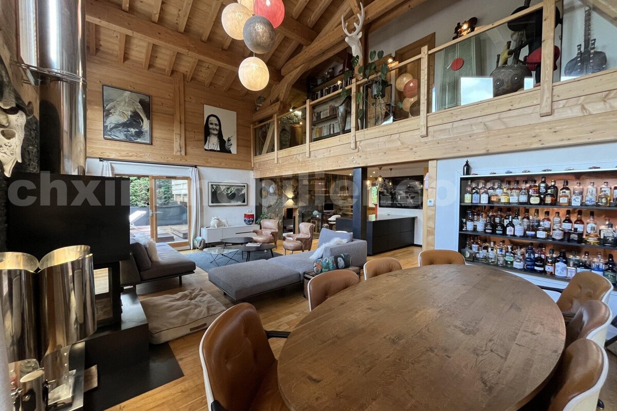A grand, rustic-modern chalet interior featuring wood paneling, a dining area, cozy lounge, mezzanine, and a large liquor display.