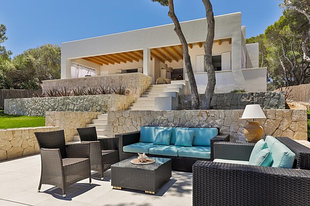 A patio with a couch and chairs in front of a house