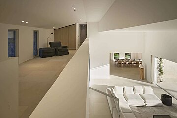 A bright, modern multi-level home interior features white walls, light floors, and neutral furniture, including a living area, upstairs lounge, and dining room.