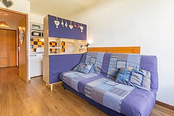 A living room with a purple couch and hearts hanging on the wall