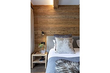 A bedroom with a wooden wall and a bed