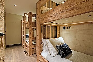 A room with bunk beds and a couch with pillows on it