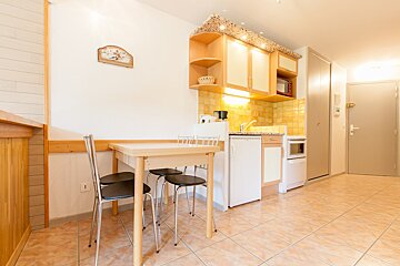 A kitchen with a table and chairs and a clock on the wall