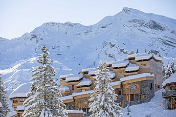 A snowy mountain behind a row of snow covered buildings