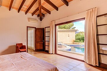 A bedroom with a sliding glass door leading to a pool
