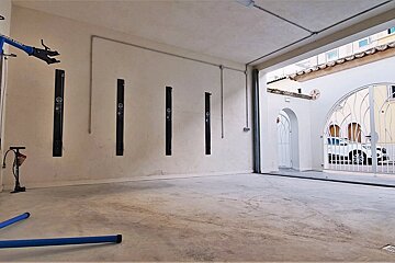 An empty garage with a white car parked in the background
