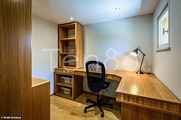 A desk with a chair and a lamp in a room with the number 80 on the wall