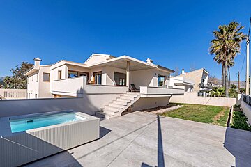 A white house with a swimming pool in front of it