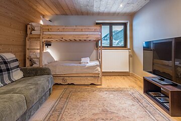 A living room with a bunk bed and a flat screen tv