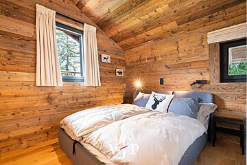 A bedroom with wood paneling and a bed with a deer pillow