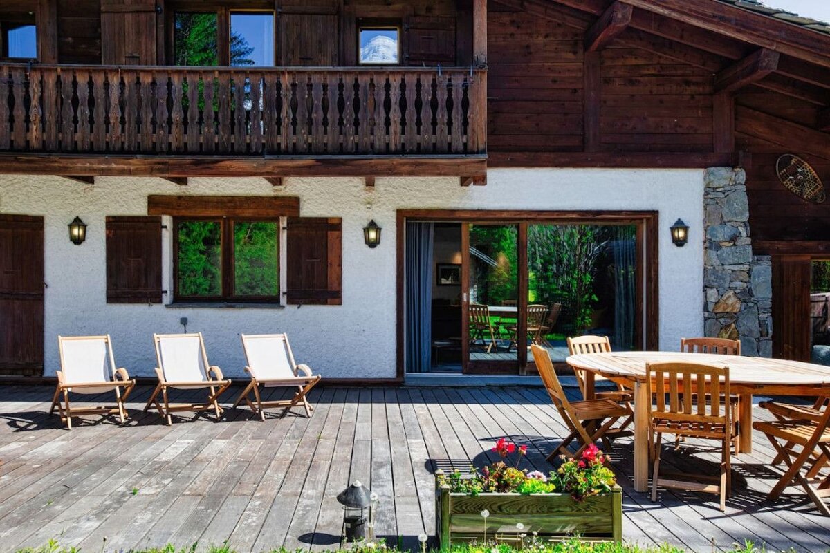 A wooden deck with a table and chairs in front of a house