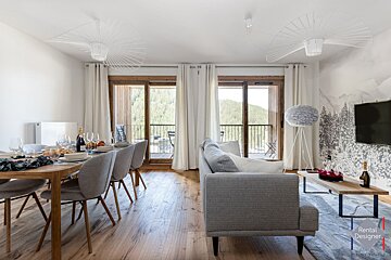 A living room with a gray couch and a rental designer logo