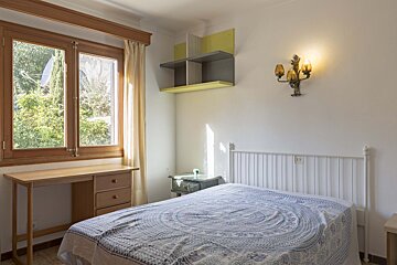 A bedroom with a bed a desk and a window