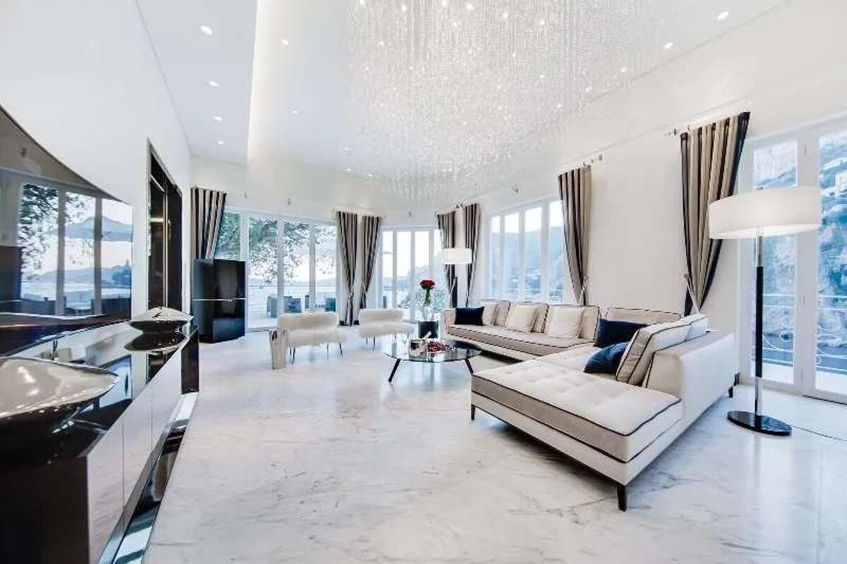 A luxurious, bright living room featuring a sparkling ceiling, white marble floors, modern furniture, and large windows with a scenic view.
