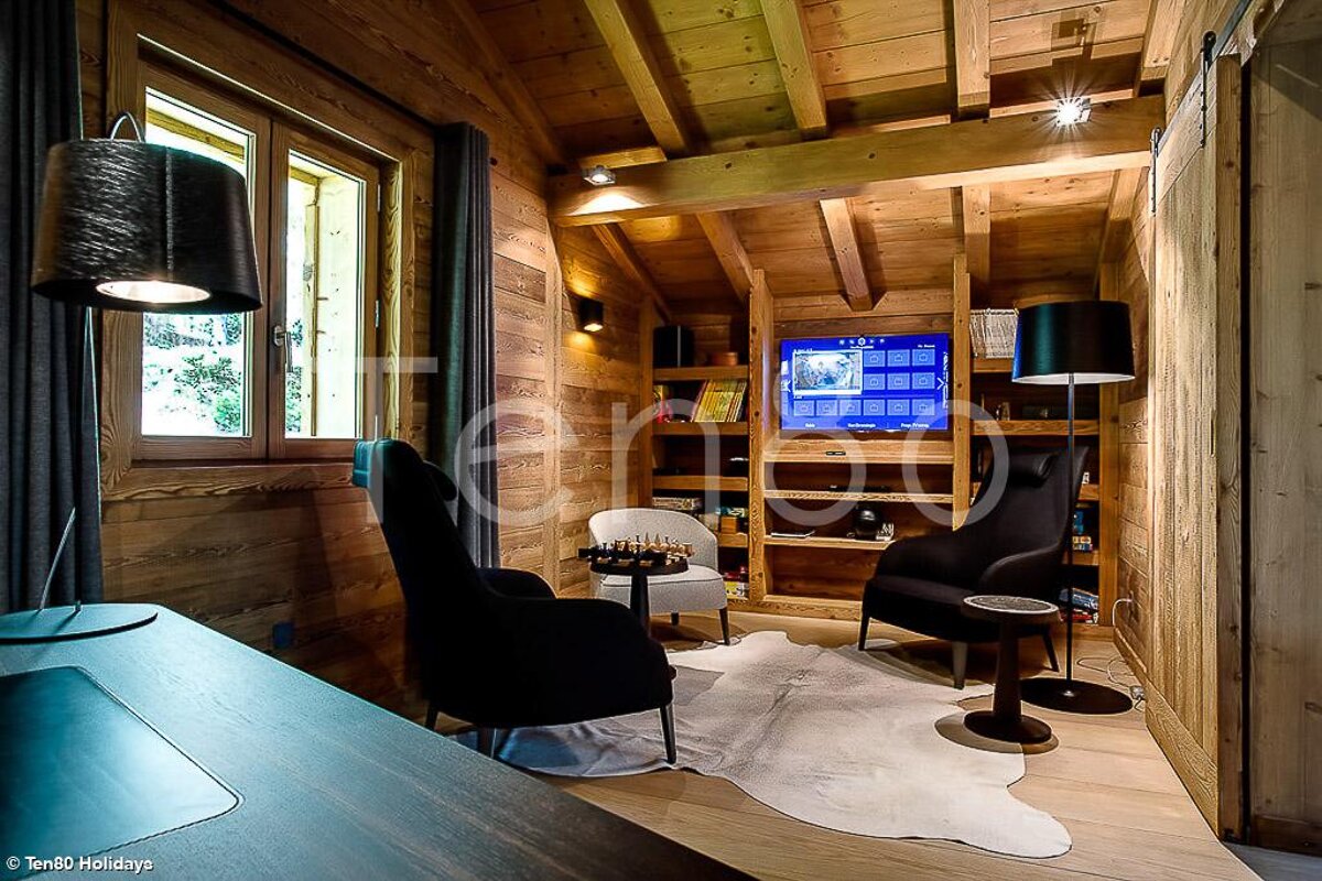 A wooden room with two chairs and a flat screen tv