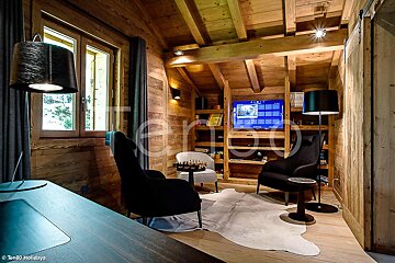 A wooden room with two chairs and a flat screen tv