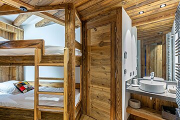 A bunk bed is next to a sink in a wooden room