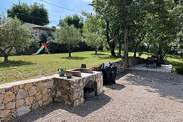 A stone wall surrounds a yard with a slide in the background