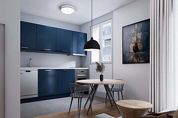 A modern kitchen and dining area with navy blue cabinets, white countertops, a round wooden table, grey chairs, and an abstract painting.