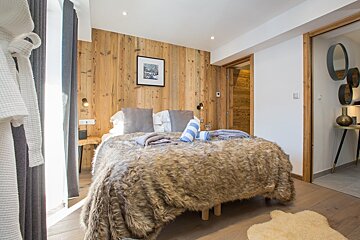 A bedroom with a fur blanket and a picture on the wall