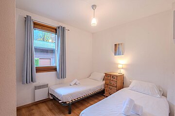 A bedroom with two beds and a table with a lamp