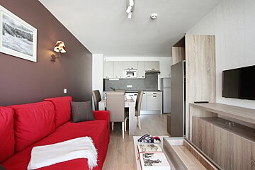 A living room with a red couch and a television