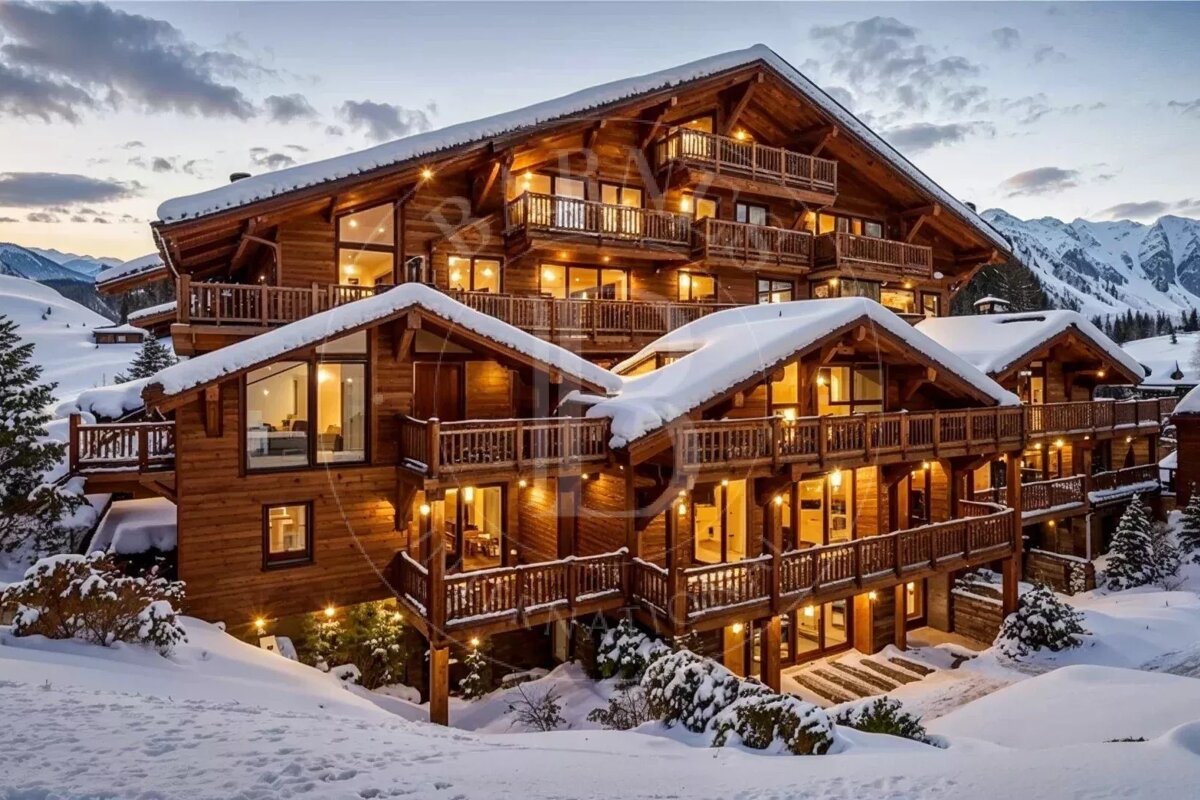 A grand wooden chalet covered in snow, with warm lights glowing, set against a backdrop of snowy mountains at dusk.