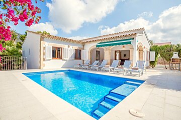 A white house with a large swimming pool in front of it
