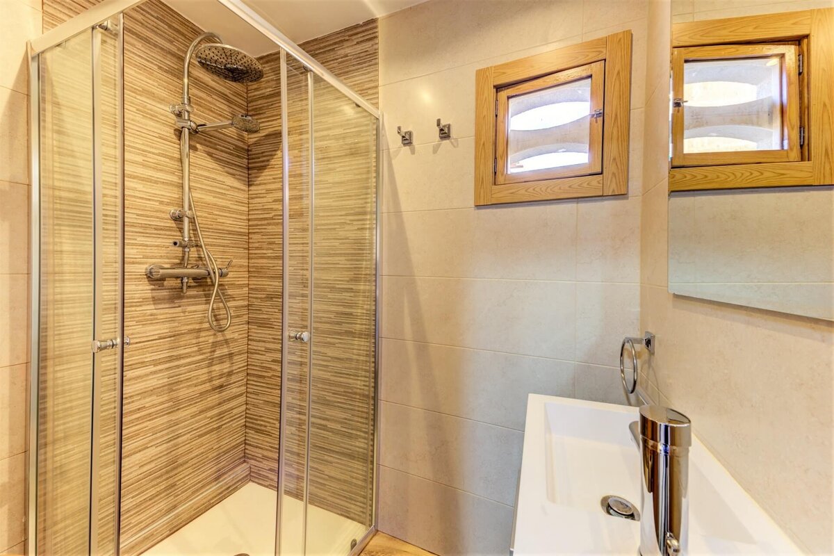 A bathroom with a walk in shower and a sink
