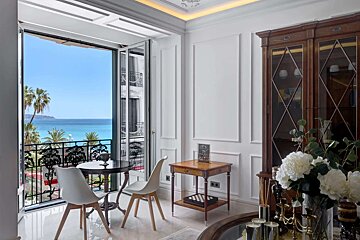A room with a table and chairs and a view of the ocean