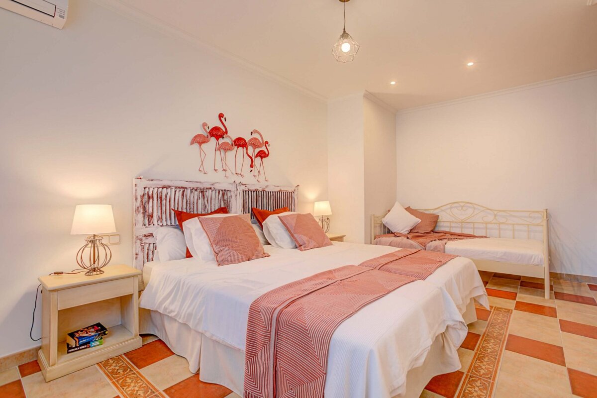 A bedroom with two beds and flamingos on the wall